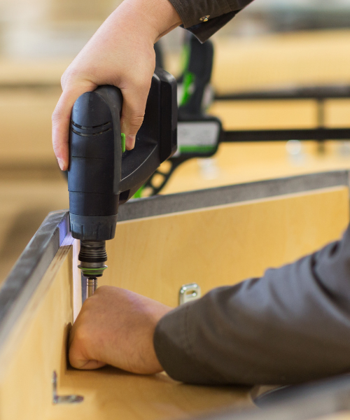 A person using a drill to drill a piece of wood